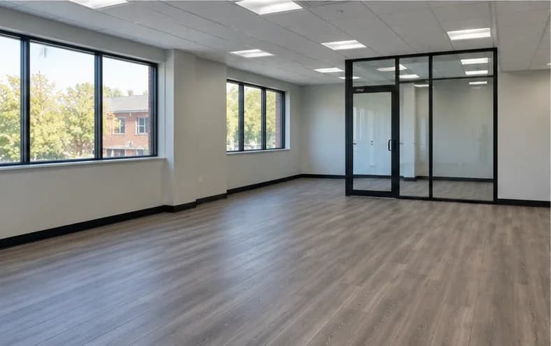 A finished, empty commercial office suite with new plank flooring, fresh paint and a glass-walled office