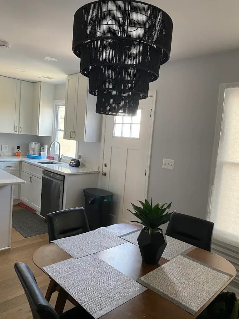 Open-plan kitchen and dining area finished by All Purpose Anytime Services, with painted walls, new lighting and wood flooring