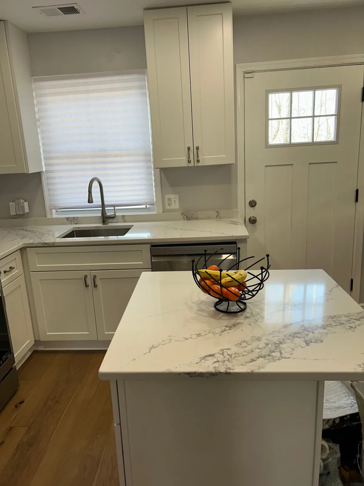 Remodeled kitchen by All Purpose Anytime Services with quartz counters, an undermount sink and new wood flooring